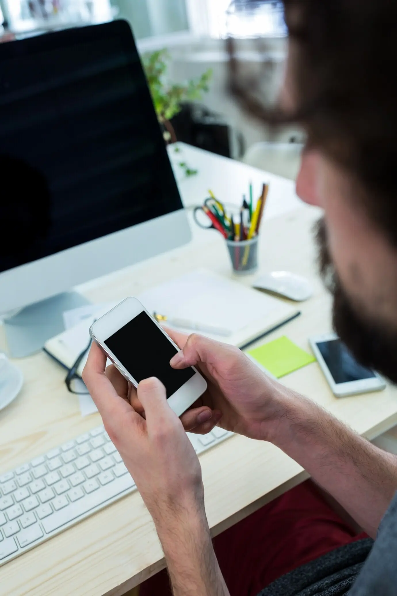 Графический дизайнер-мужчина использует мобильный телефон.